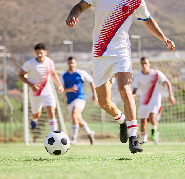 Fußballer läuft am Fußballplatz mit dem Ball am Fuß